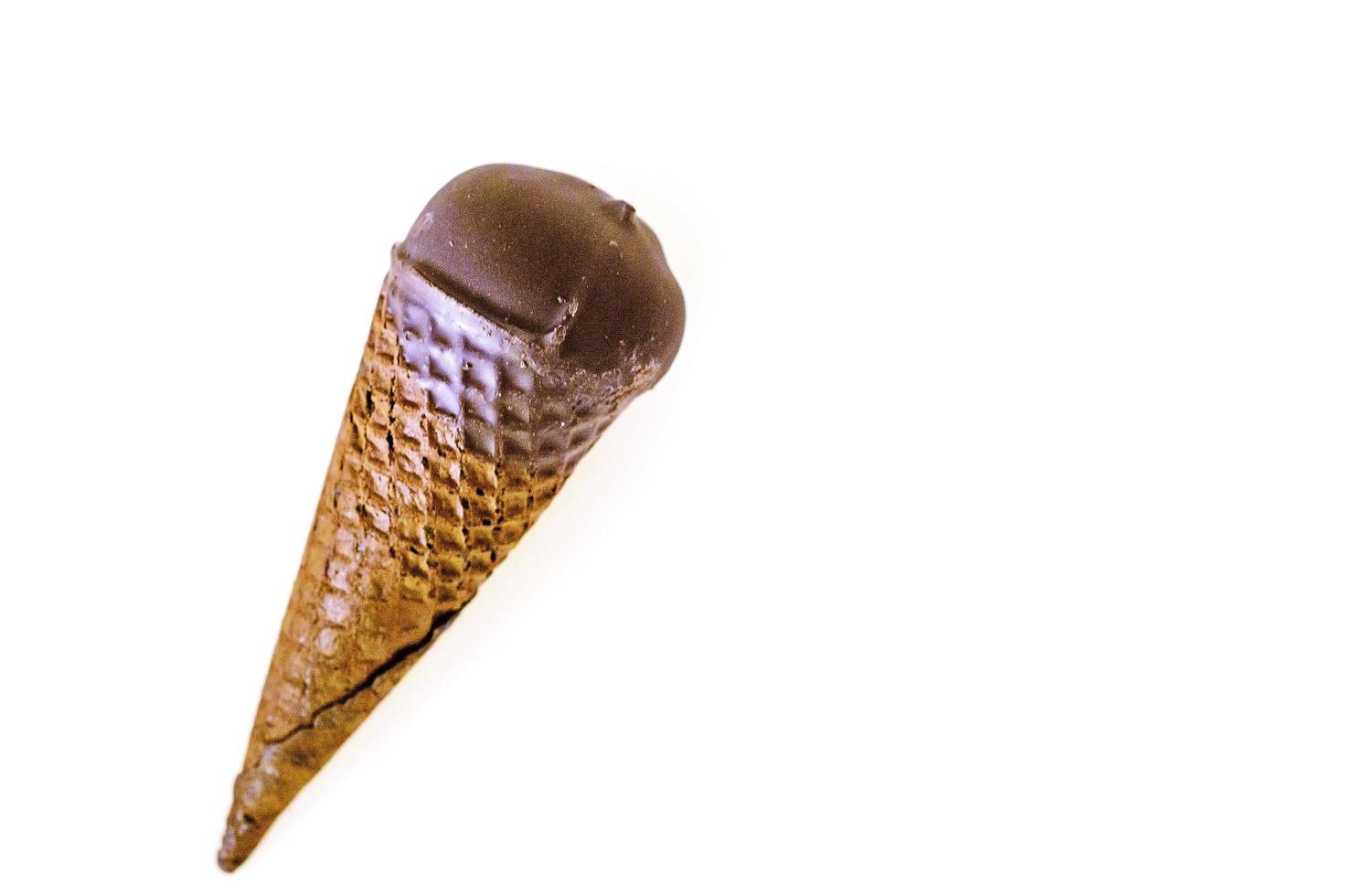 gelato alla vaniglia con marmellata di mirtilli rossi in un cono di zucchero immerso nel cioccolato isolato su sfondo bianco. foto