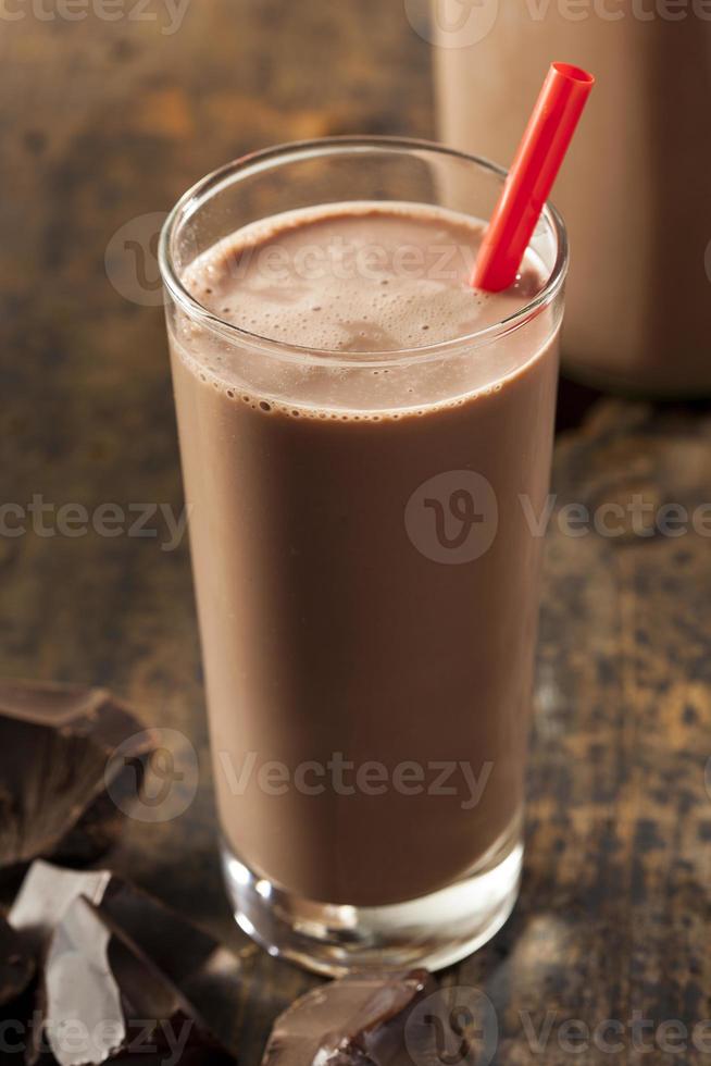 bicchiere di latte al cioccolato con paglia rossa su un tavolo di legno foto