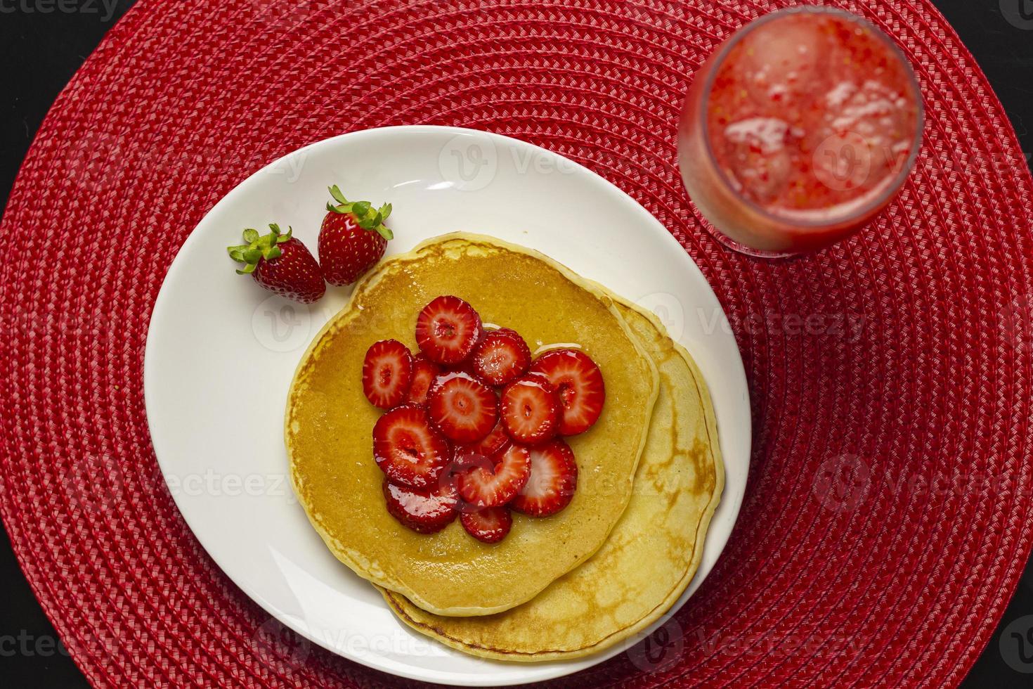 vista dall'alto del pancake fatto in casa con fragole e sciroppo foto