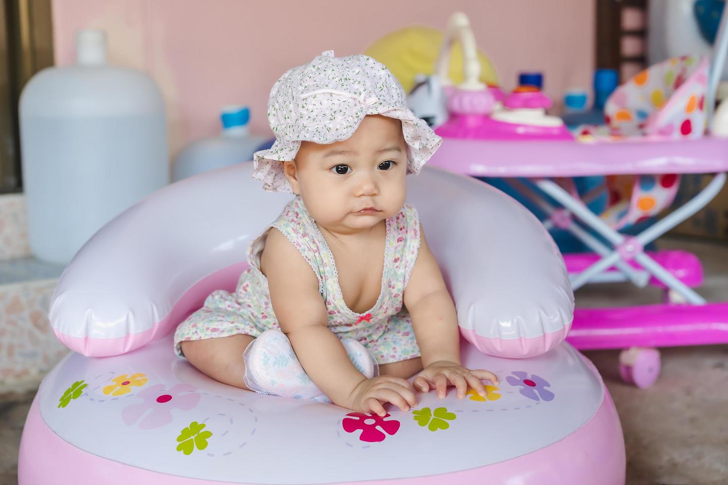 ritratto di una piccola bambina asiatica che guarda o qualcosa o sua madre su una sedia gonfiabile durante la pandemia di coronavirus covid-19 foto