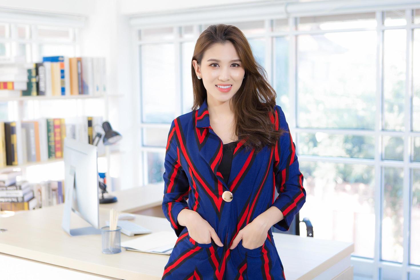 bella donna asiatica professionale che indossa una signora dell'ufficio camicia a maniche lunghe in piedi e sorridente al lavoro sorridente felicemente in ufficio sta guardando la telecamera e mettere la mano in tasca. foto