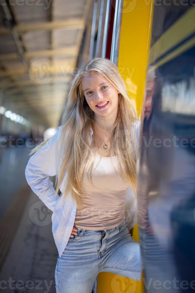 ritratto di una bella giovane donna bionda in piedi in treno. foto