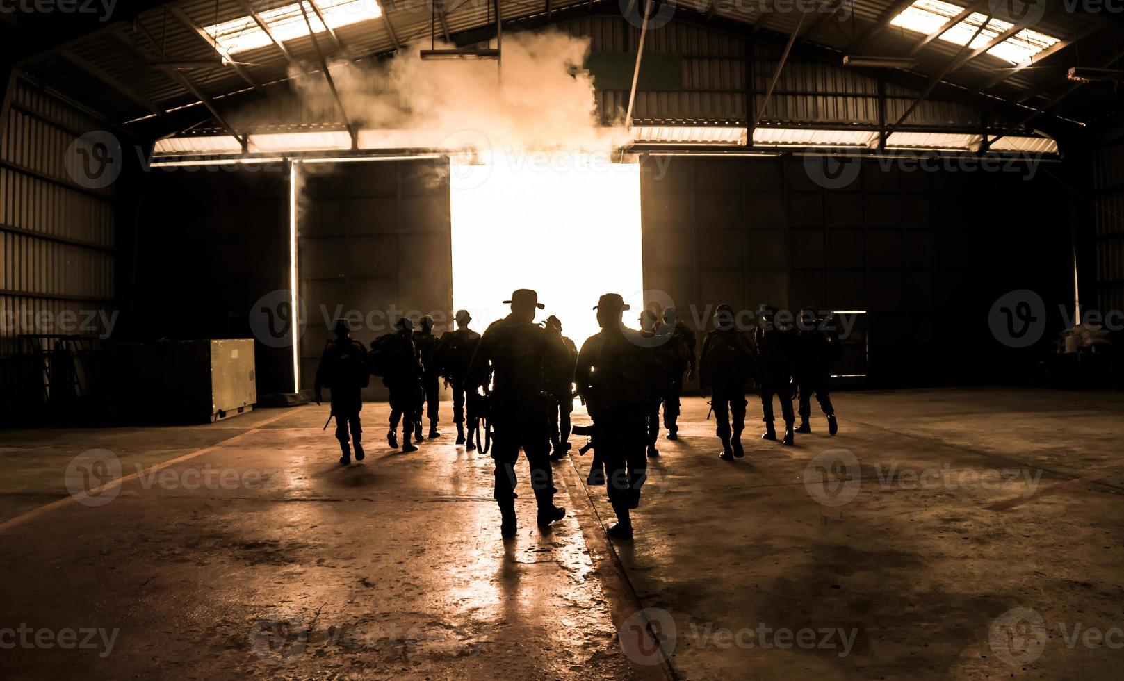 sagome di soldati dell'esercito nella nebbia contro un tramonto, squadra di marines in azione, circondato da fuoco e fumo, sparando con fucile d'assalto e mitragliatrice, attaccando il nemico foto