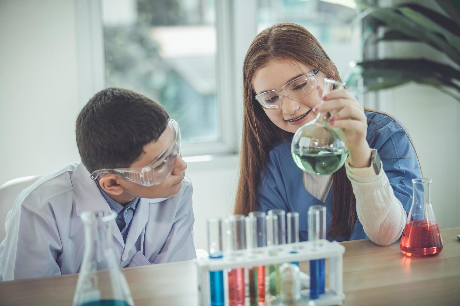 gli studenti mescolano sostanze chimiche nei bicchieri. studente di chimica mescola sostanze chimiche nella classe di scienze foto