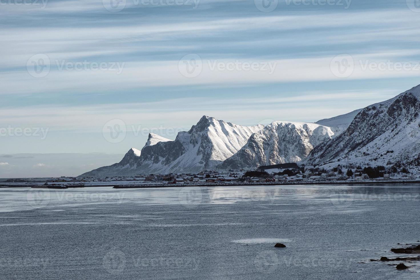 scenario della catena montuosa della neve con il villaggio norvegese sulla costa foto