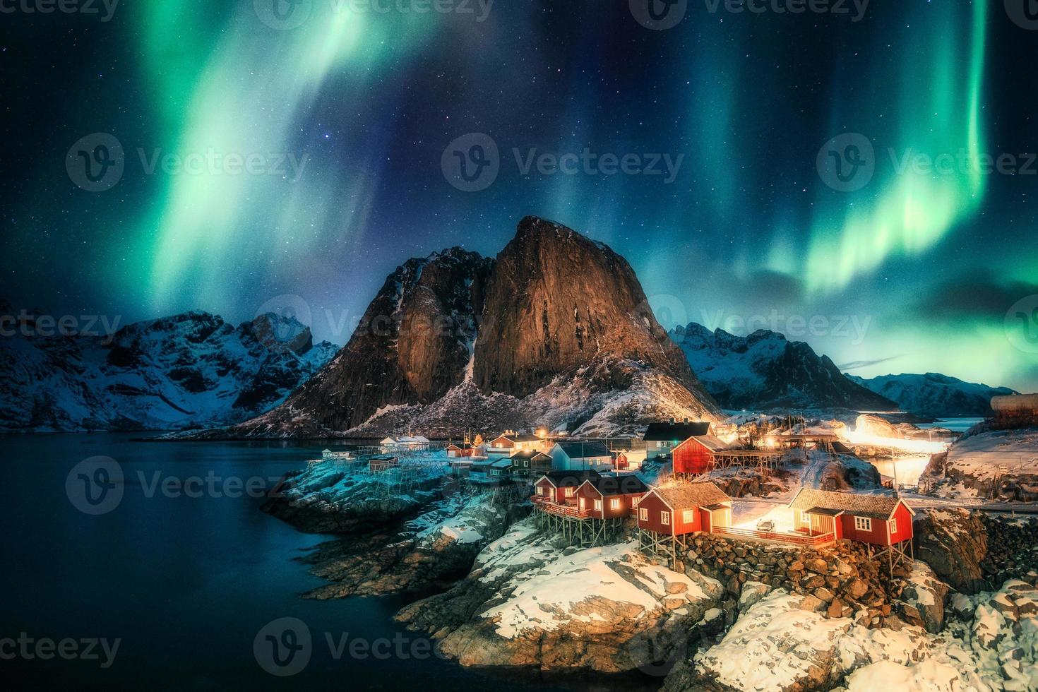 aurora boreale, aurora boreale sulla montagna con villaggio di pescatori sulla costa ad hamnoy, isole lofoten foto