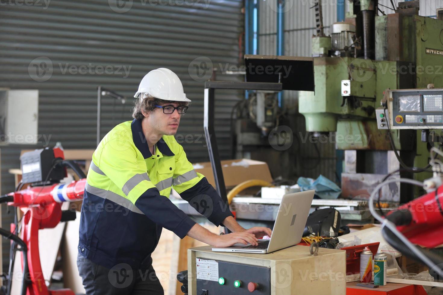 dipendente di una fabbrica industriale professionale che lavora con parti di macchine, controlla e testa apparecchiature industriali e bracci robotici in una grande fabbrica di impianti per la produzione di cavi e fili di elettronica elettrica foto