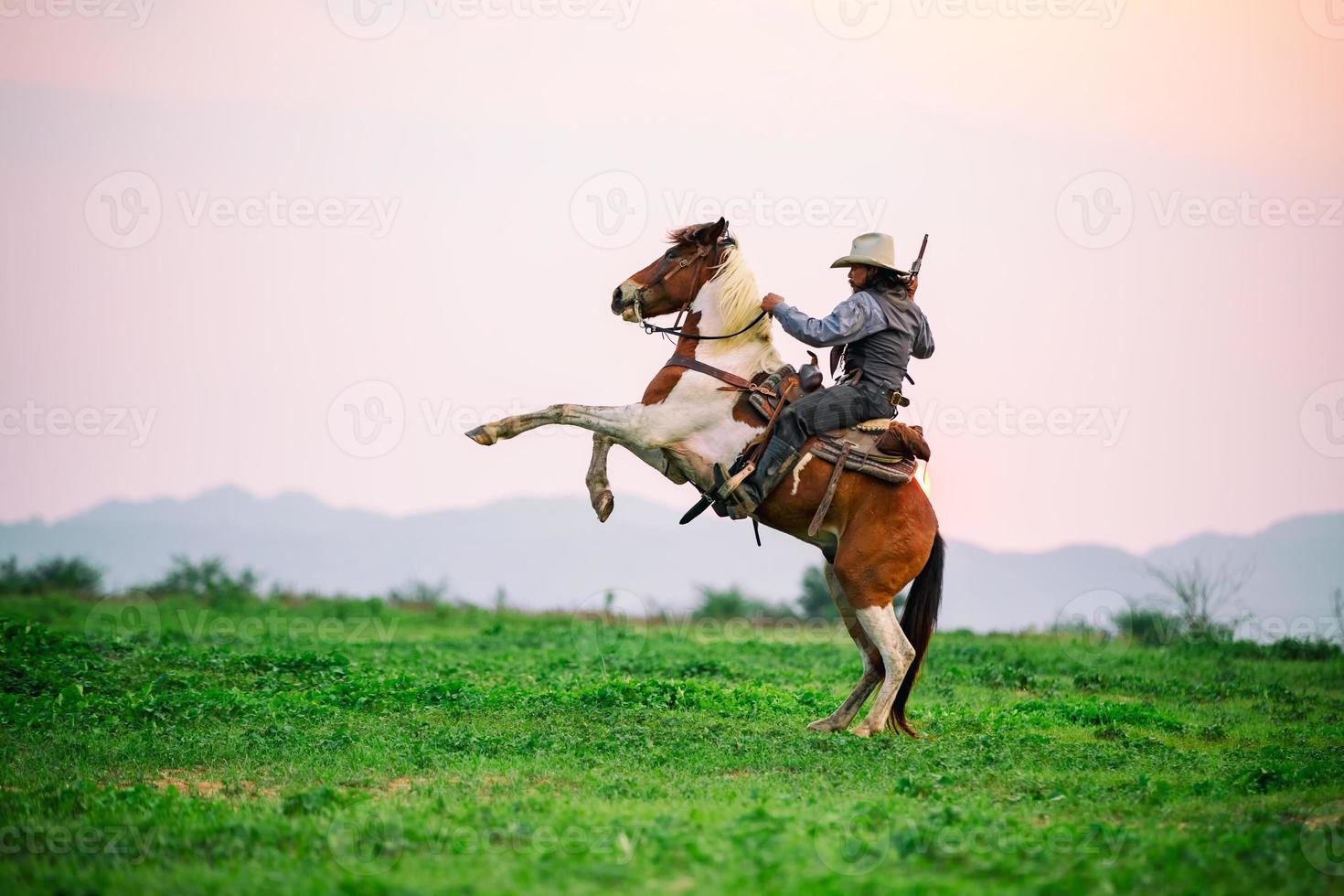 cowboy a cavallo contro un bel tramonto, cowboy e cavallo alle prime luci, montagna, fiume e stile di vita con sfondo di luce naturale foto