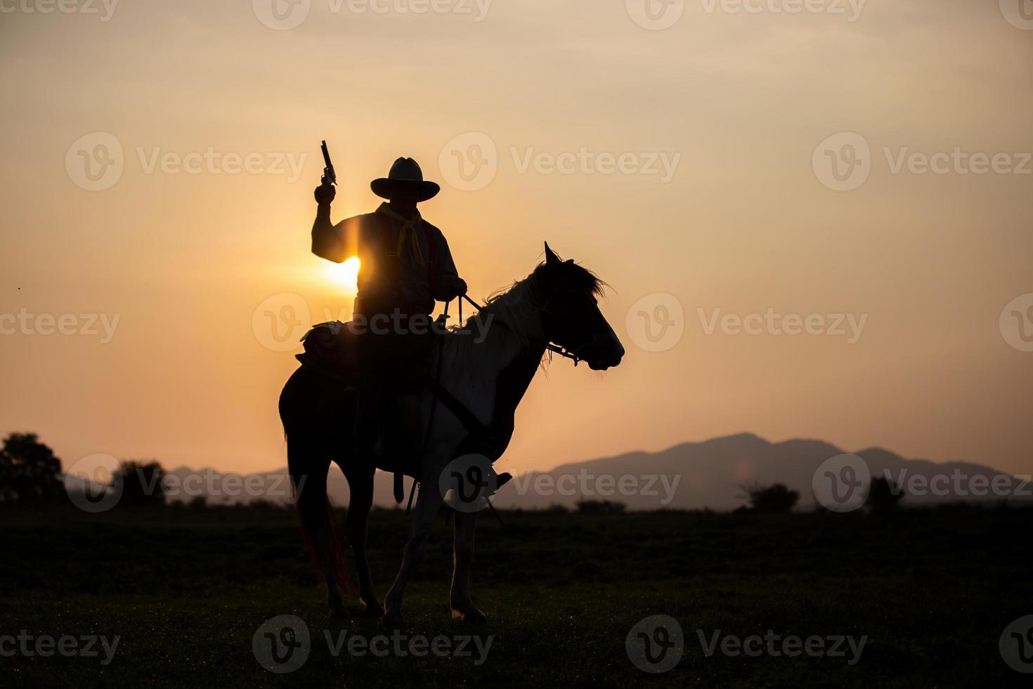 silhouette cowboy a cavallo contro un bel tramonto, cowboy e cavallo alle prime luci, montagna, fiume e stile di vita con sfondo di luce naturale foto