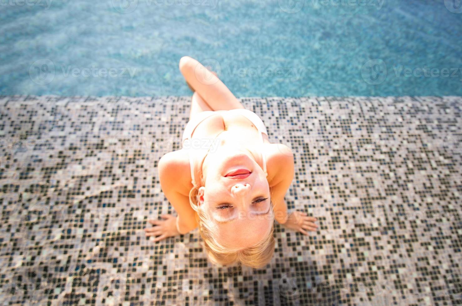 giovane donna godendo e rilassante a bordo piscina. modello di ragazza snella in bikini bianco a bordo piscina. foto