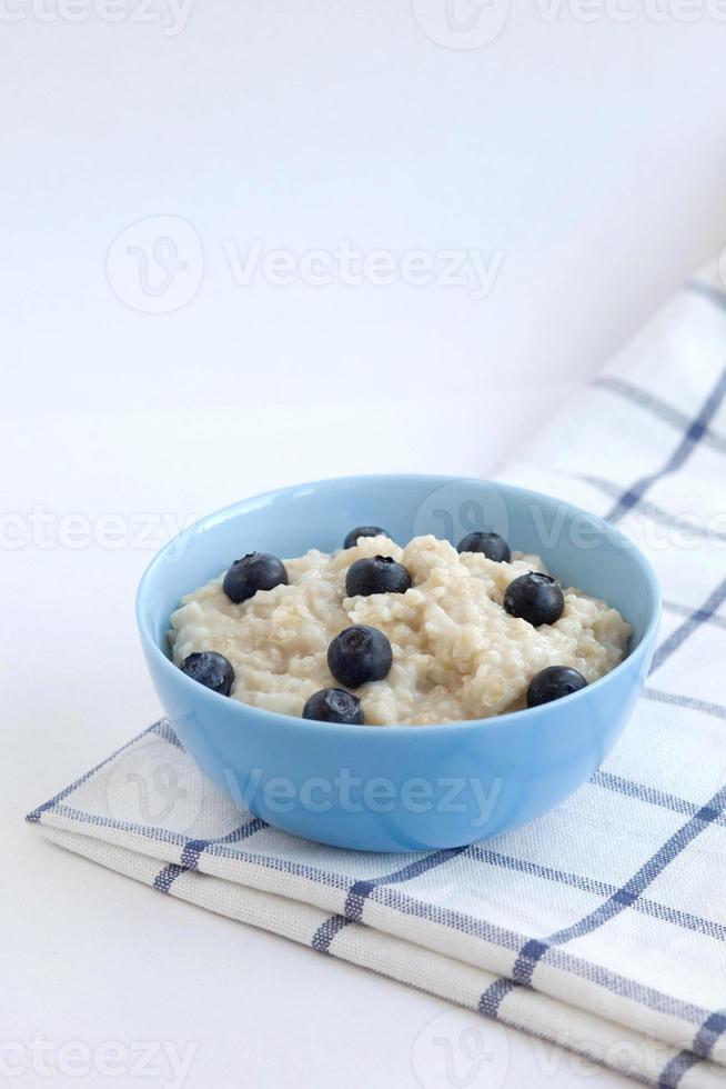 porridge di farina d'avena con mirtilli in un piatto blu su un tovagliolo a scacchi. fotografia di cibo foto