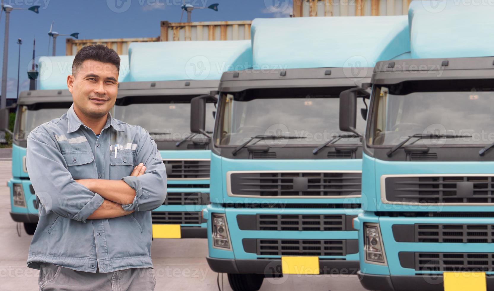 maturo uomo asiatico occupazione camionista sorridente fiducioso ottimista in piedi con le braccia incrociate orgoglioso. sfondo semi-camion container trasporto consegna spedizione parco in magazzino al porto. foto