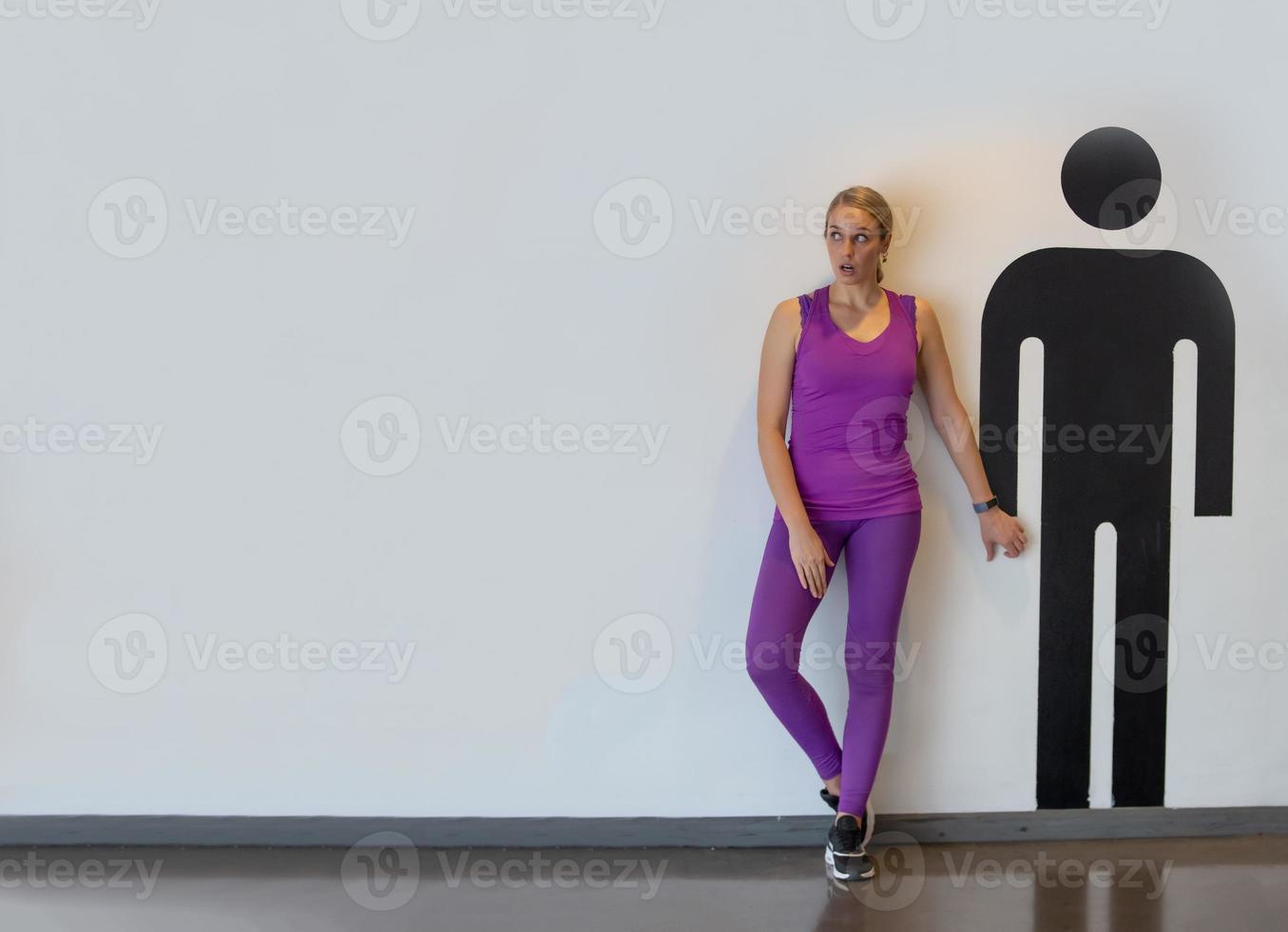 ritratto di donne con abbigliamento sportivo in piedi accanto al personaggio grafico degli uomini contro il muro bianco foto