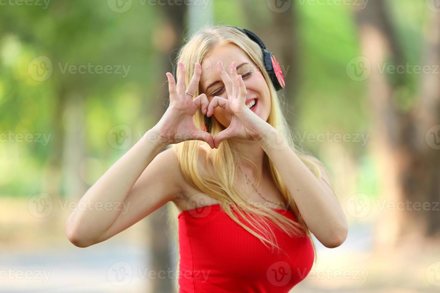 bella donna bionda in piedi mentre si ascolta musica in cuffia al parco. foto