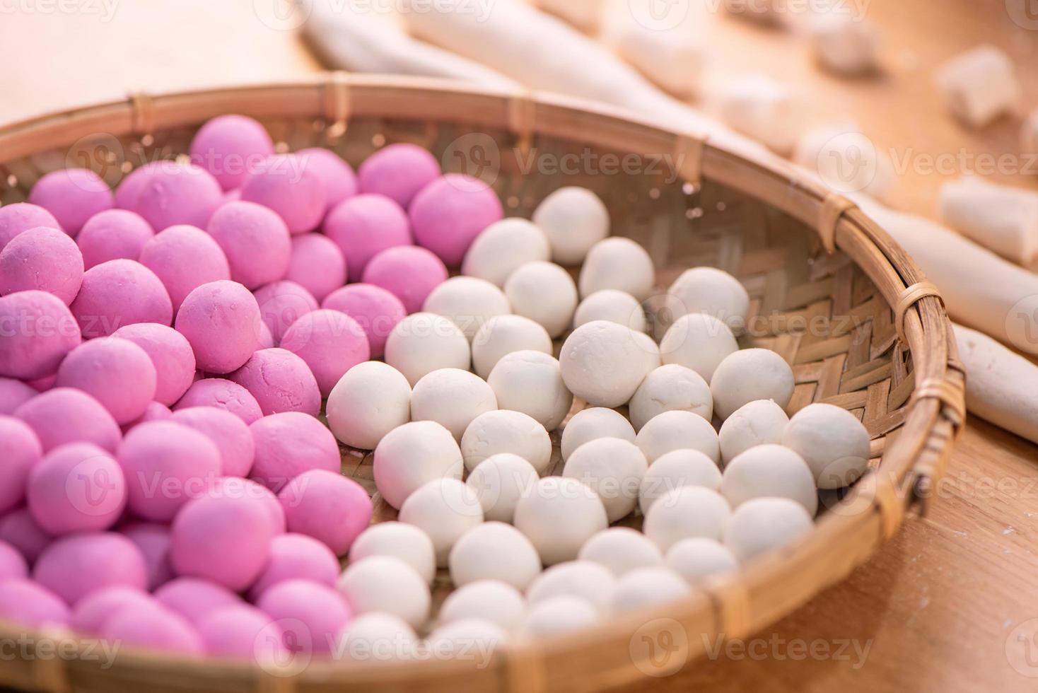 una donna asiatica sta facendo tang yuan, yuan xiao, gnocchi di riso tradizionali cinesi in rosso e bianco per il capodanno lunare, festival invernale, primo piano. foto