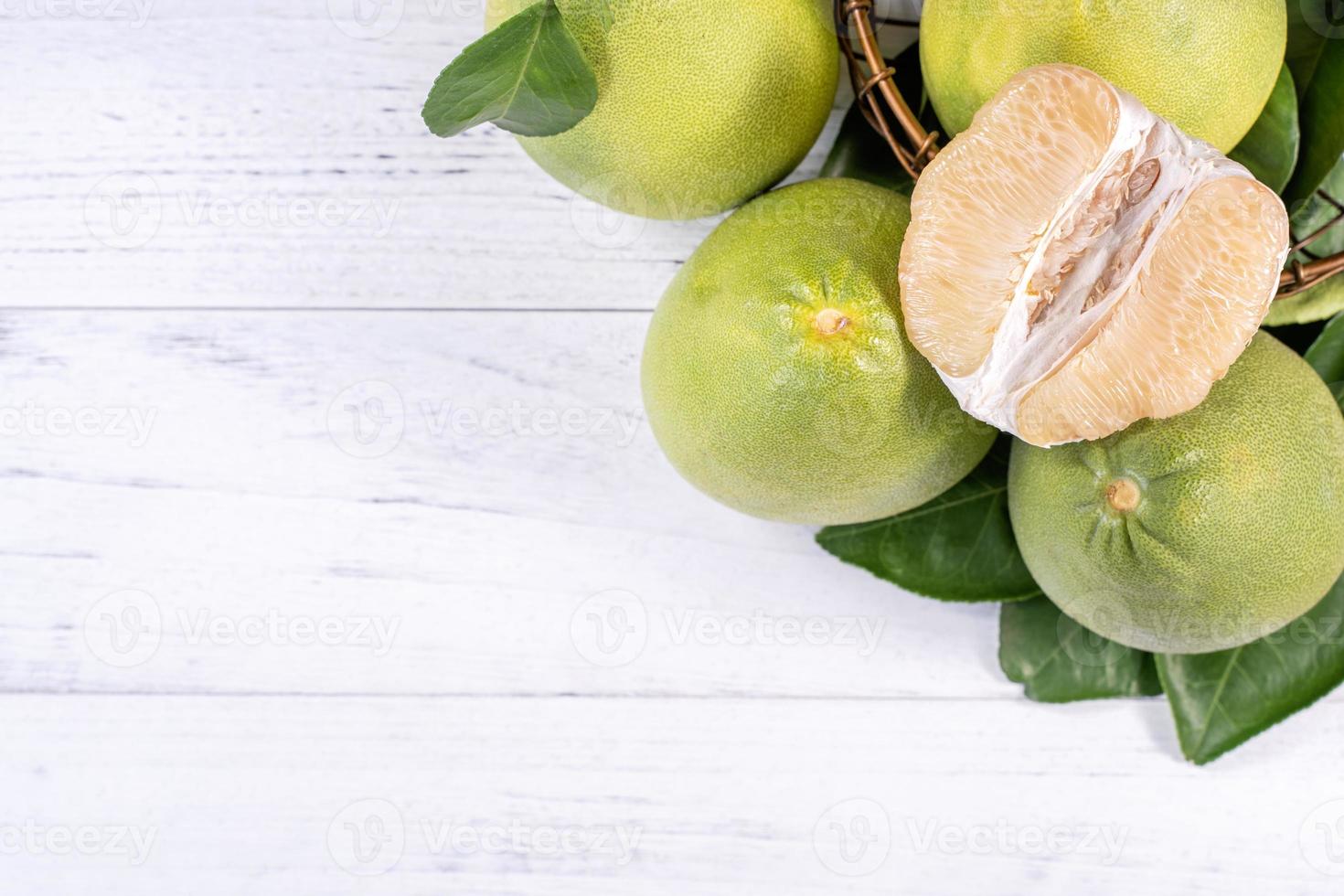 pomelo fresco sbucciato, pummelo, pompelmo, shaddock su fondo di legno luminoso. frutta di stagione autunnale, vista dall'alto, posa piatta, colpo da tavolo. foto