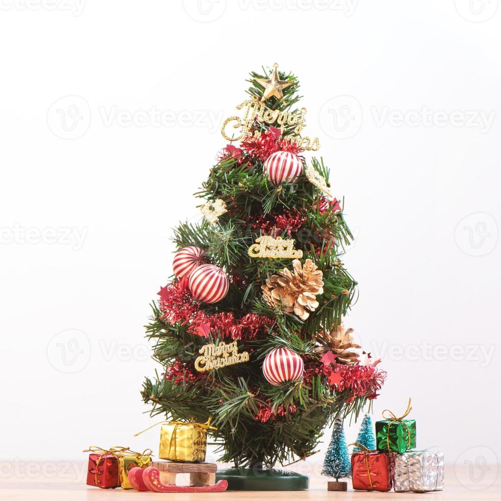 albero di natale decorato carino su un pavimento di legno con sfondo bianco e giocattoli, vuoto per il concetto di design festivo, primo piano. foto