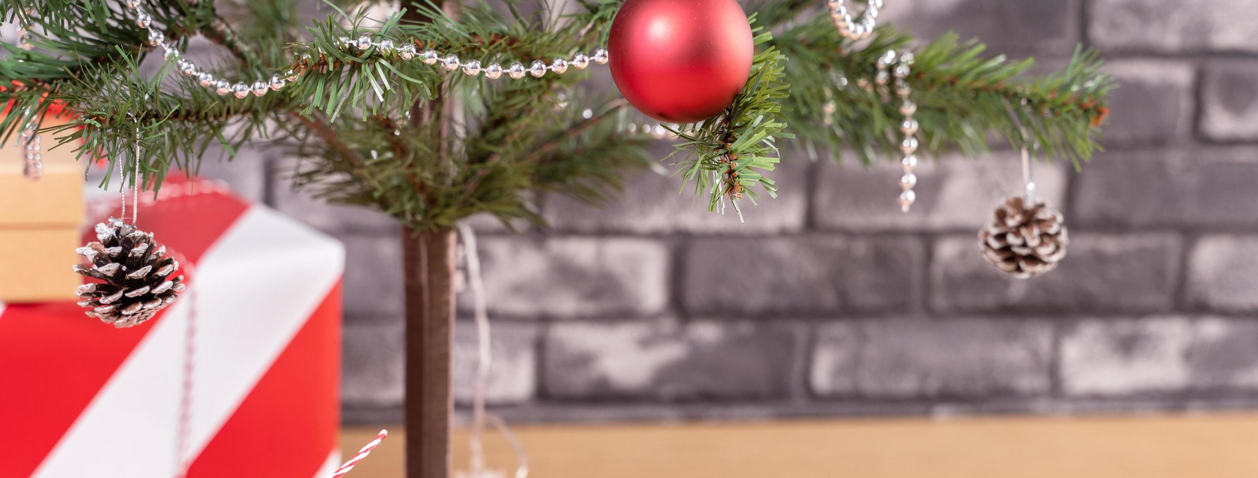 albero di natale decorato con bellissimi regali rossi e bianchi avvolti a casa con muro di mattoni neri, concetto di design festivo, primo piano. foto