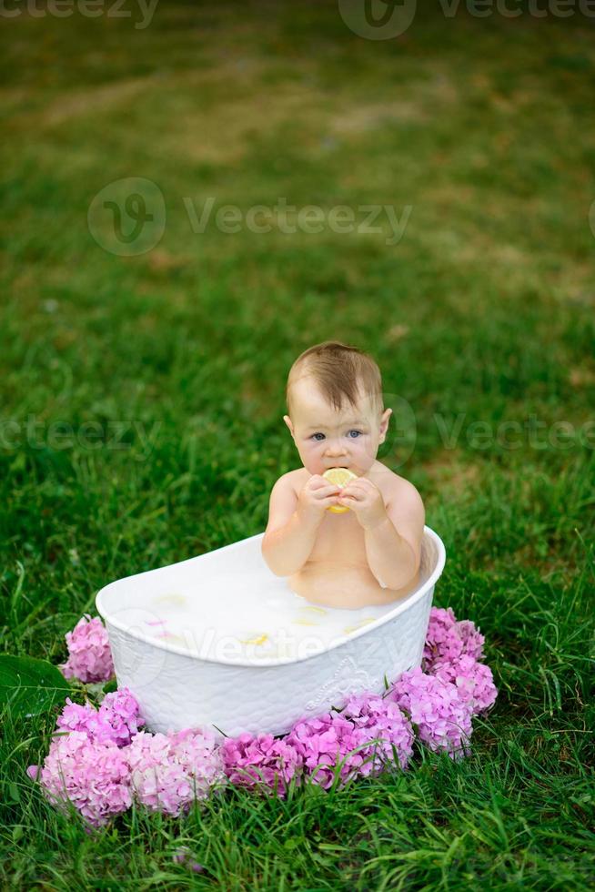 bambina si bagna in un bagno di latte nel parco. la ragazza si diverte in estate. foto