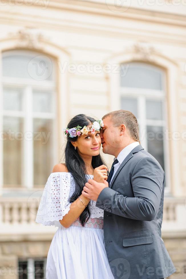 servizio fotografico di matrimonio sullo sfondo del vecchio edificio. lo sposo guarda la sua sposa in posa. fotografia di matrimonio rustica o boho. foto