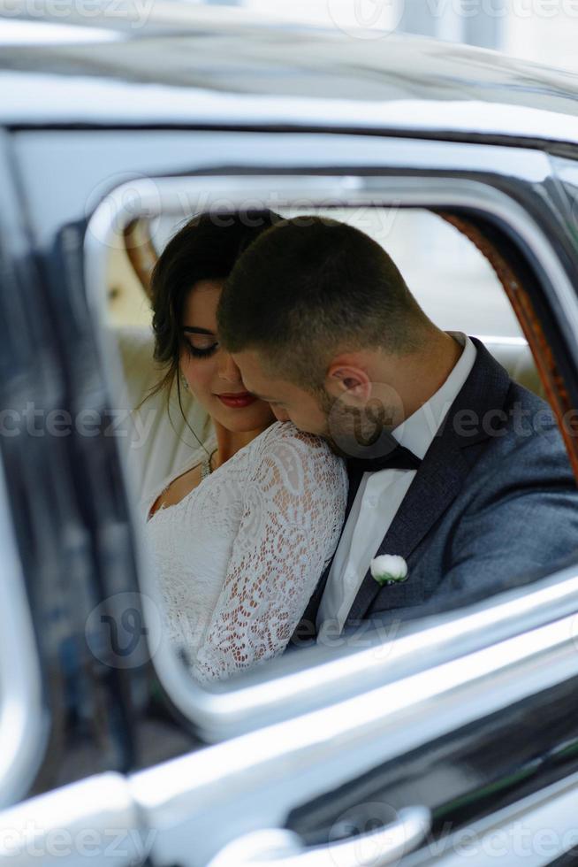 bella giovane sposa e sposo felici che guardano dall'auto retrò foto