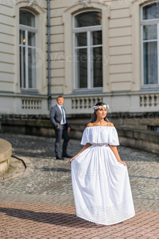 servizio fotografico di matrimonio sullo sfondo del vecchio edificio. lo sposo guarda la sua sposa in posa. fotografia di matrimonio rustica o boho. foto