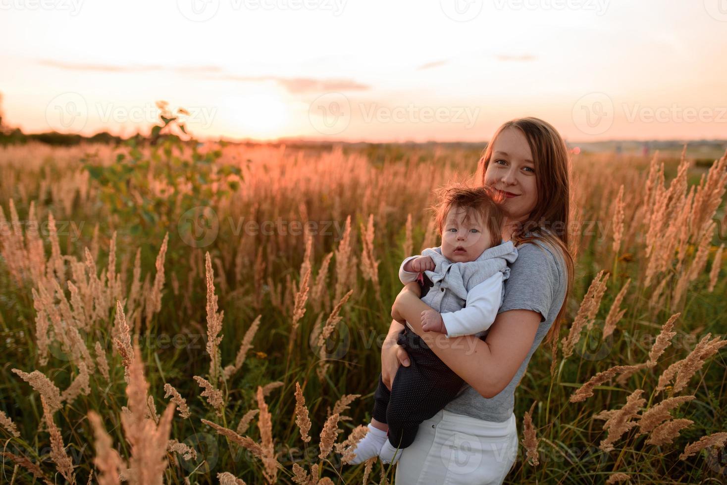 una madre passeggia nel campo con la sua piccola figlia in braccio. foto