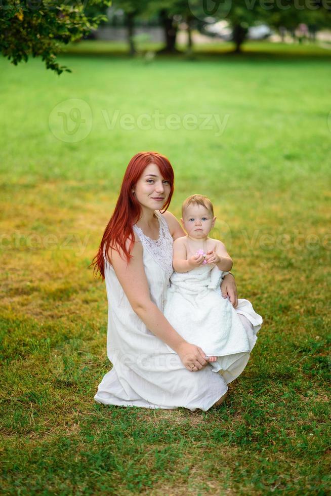 la mamma abbraccia e gioca con la figlia di un anno avvolta in un asciugamano dopo il bagno. foto