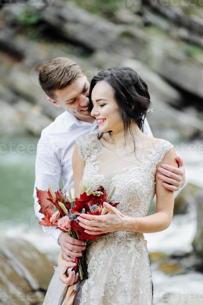 sposa e sposo. cerimonia di matrimonio vicino a un fiume di montagna foto