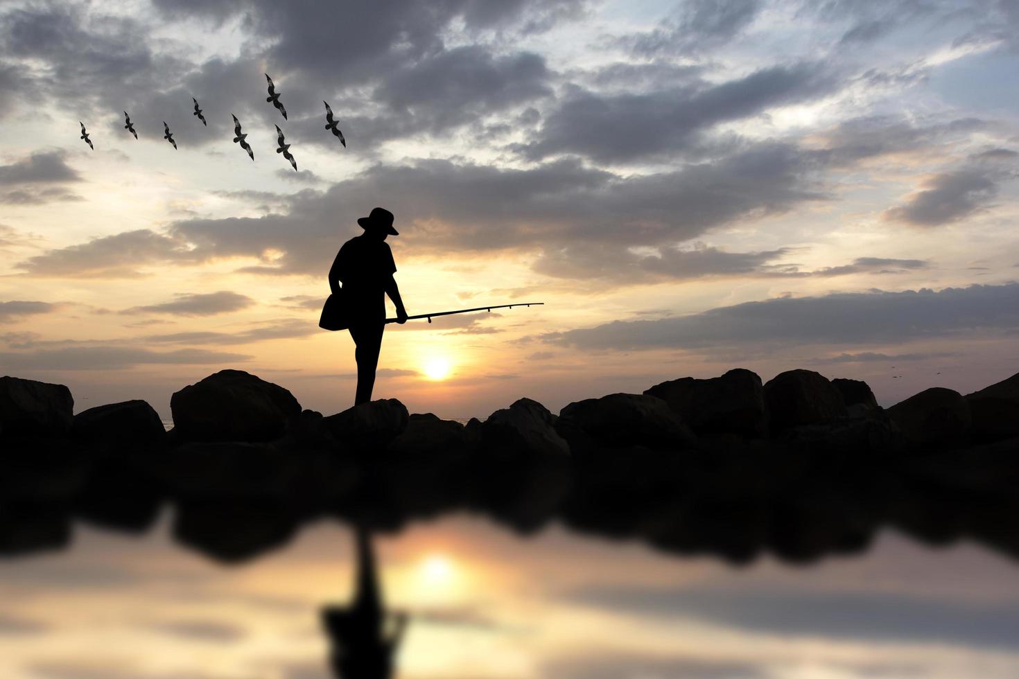 sagoma di uomo canna da pesca tramonto sullo sfondo. foto