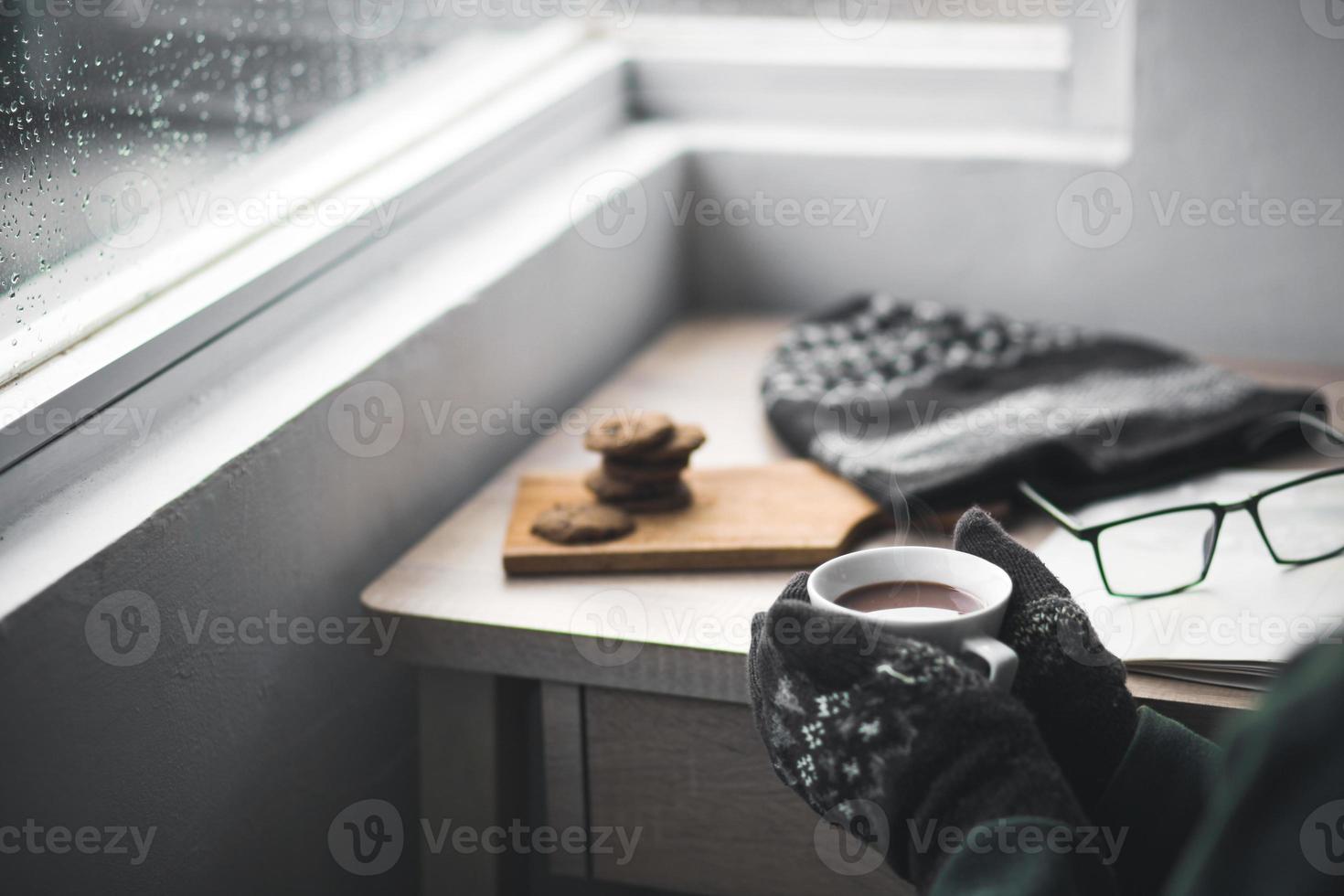 mani con guanti invernali che tengono una tazza di cioccolata calda foto