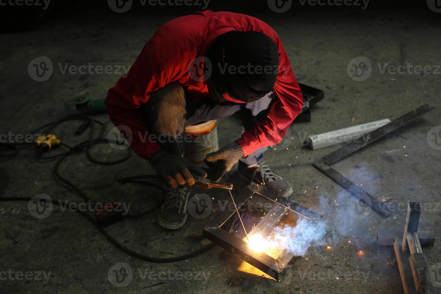 saldatore usato mola su acciaio in fabbrica con scintille, processo di saldatura presso l'officina industriale, mani con strumento nel telaio. foto