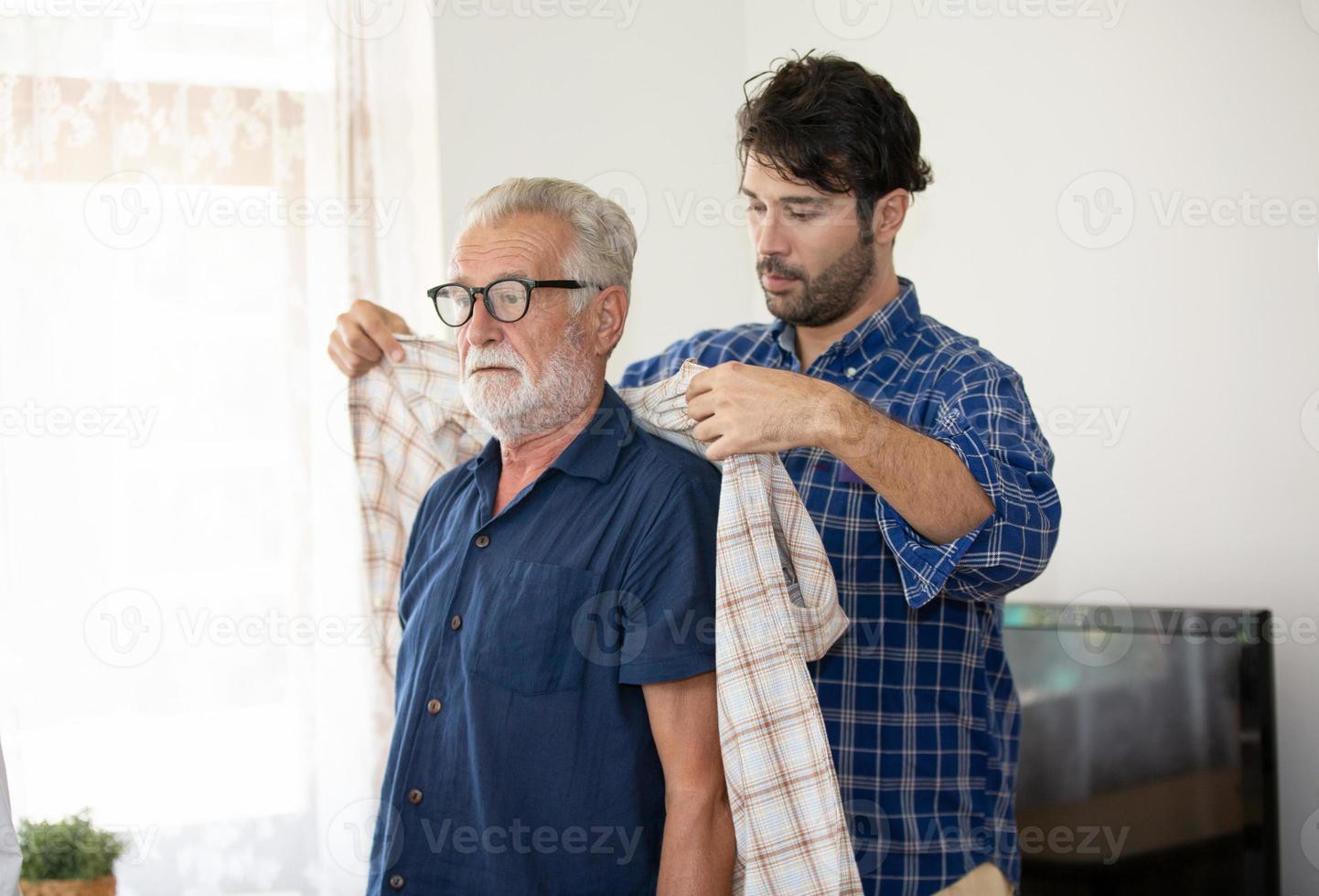 un ritratto del figlio adulto dei pantaloni a vita bassa e del padre anziano trascorrono del tempo insieme nel fine settimana a casa. foto