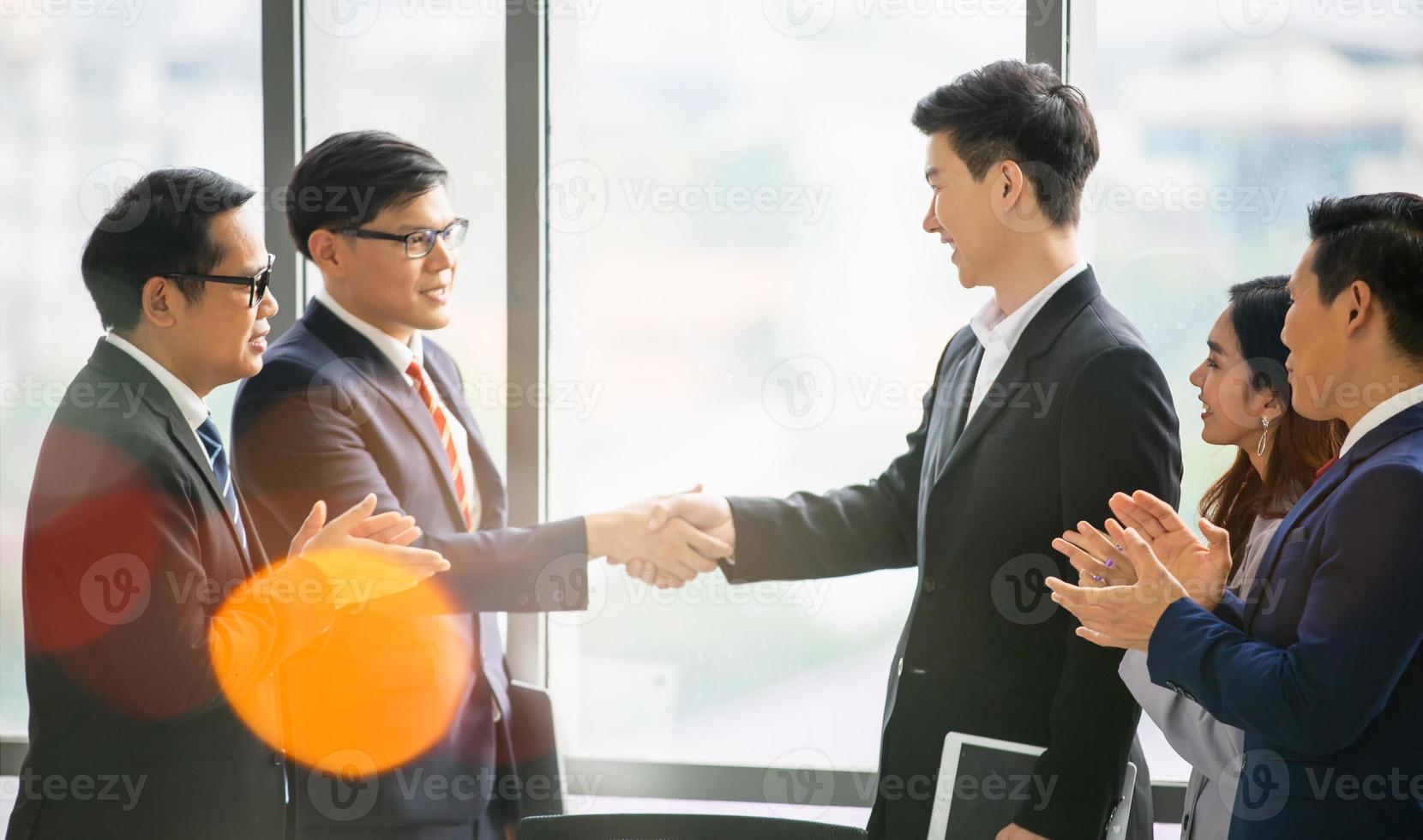 uomini d'affari che si stringono la mano nell'ufficio moderno che termina una riunione di successo foto