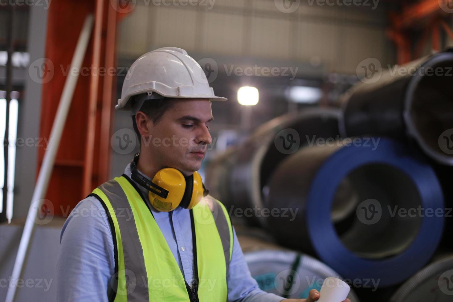 ingegnere industriale maschile che indossa un casco di sicurezza mentre si trova in una fabbrica industriale pesante. la manutenzione cercando di lavorare su macchinari industriali e controllare l'installazione del sistema di sicurezza in fabbrica. foto