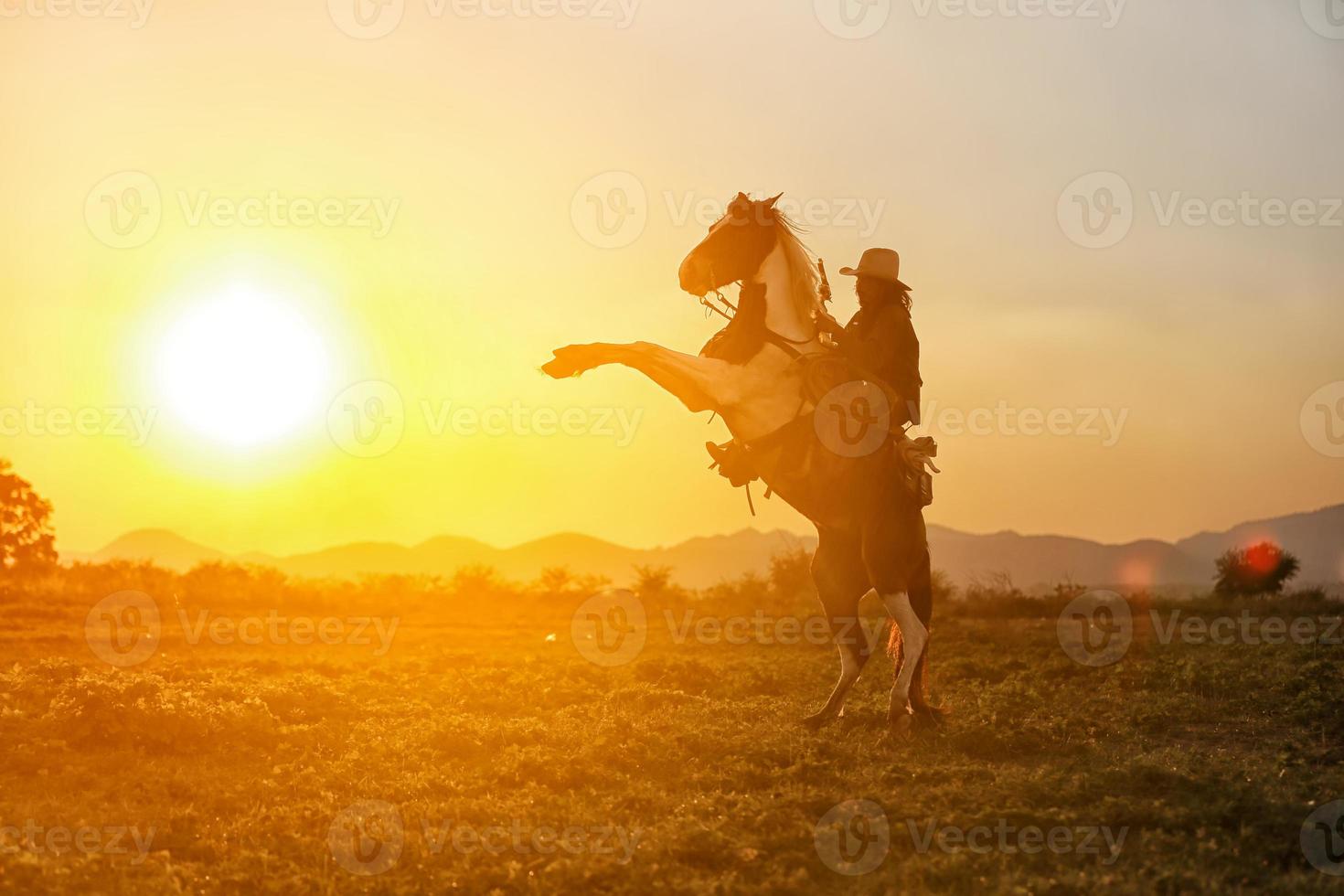 cowboy a cavallo contro un bel tramonto, cowboy e cavallo alle prime luci, montagna, fiume e stile di vita con sfondo di luce naturale foto