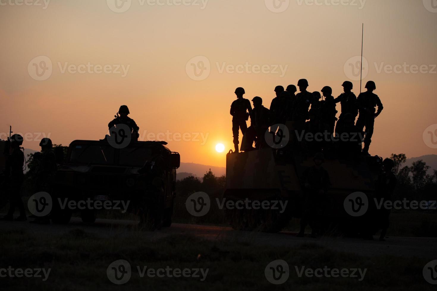 sagome di soldati dell'esercito nella nebbia contro un tramonto, squadra di marines in azione, circondato da fuoco e fumo, sparando con fucile d'assalto e mitragliatrice, attaccando il nemico foto