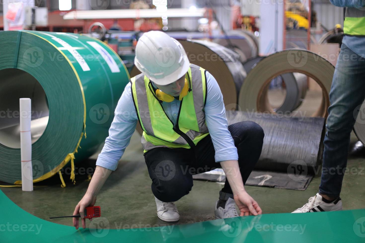 ingegnere industriale maschile che indossa un casco di sicurezza mentre si trova in una fabbrica industriale pesante. la manutenzione cercando di lavorare su macchinari industriali e controllare l'installazione del sistema di sicurezza in fabbrica. foto