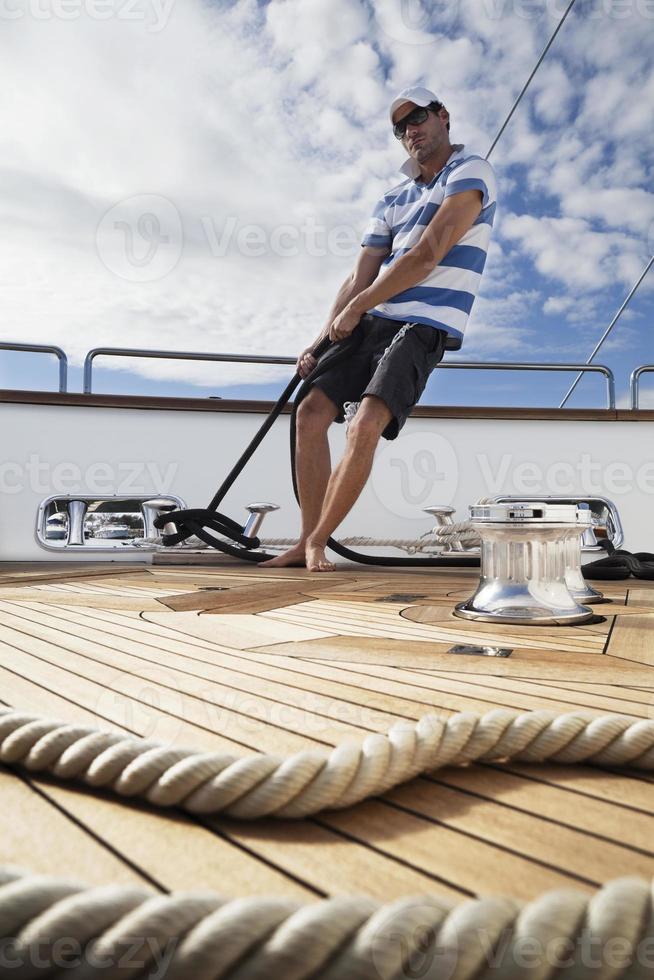 marinaio dinamico a bordo dello yacht stringendo le corde foto