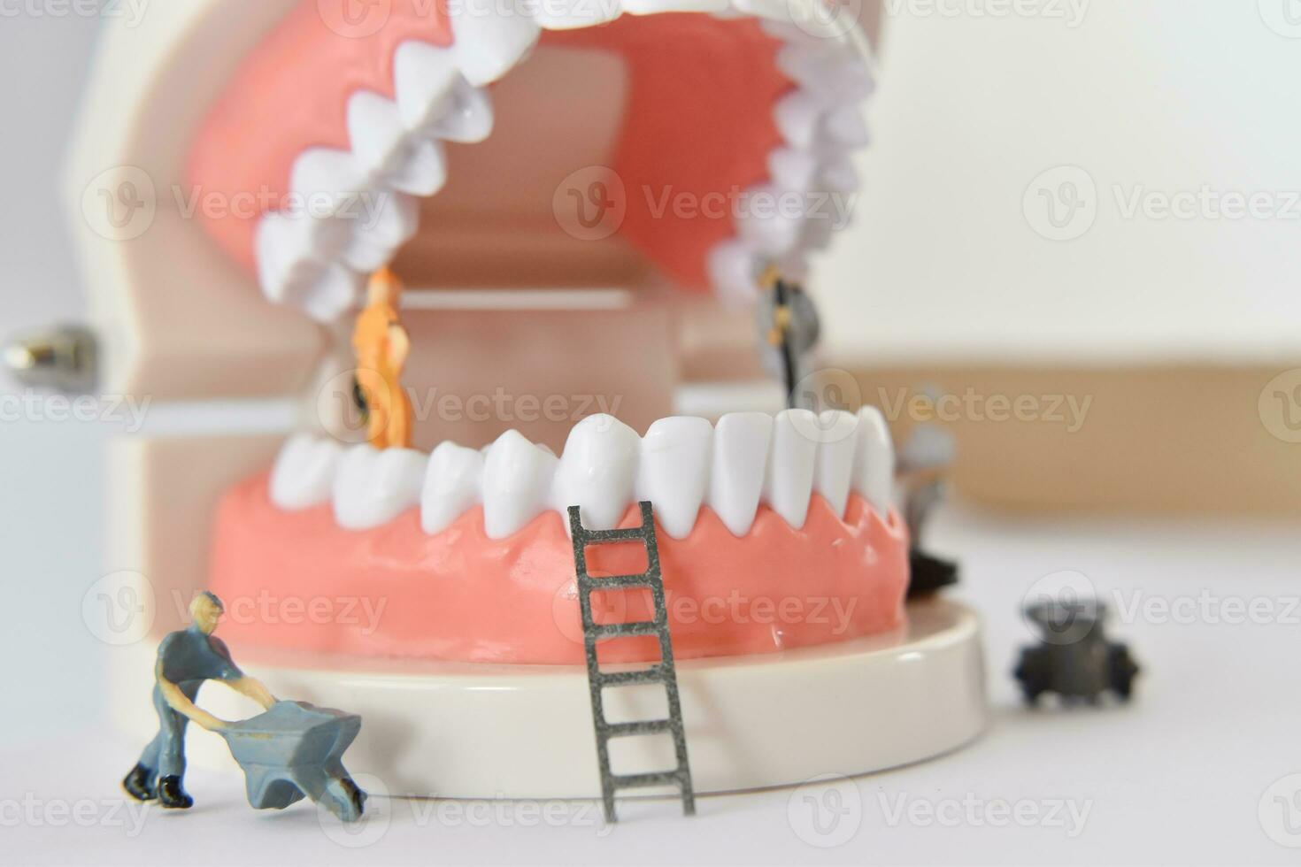 persone in miniatura per riparare un dente o un lavoratore di piccola figura che pulisce il modello di dente come medico e sanitario. foto