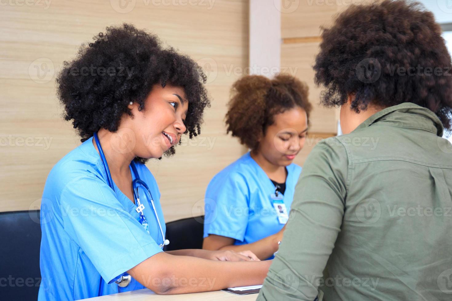 persone che prendono appuntamento con il personale medico alla reception in ospedale. personale medico e infermiere - receptionist che parla con il paziente davanti al bancone della reception in ospedale. foto