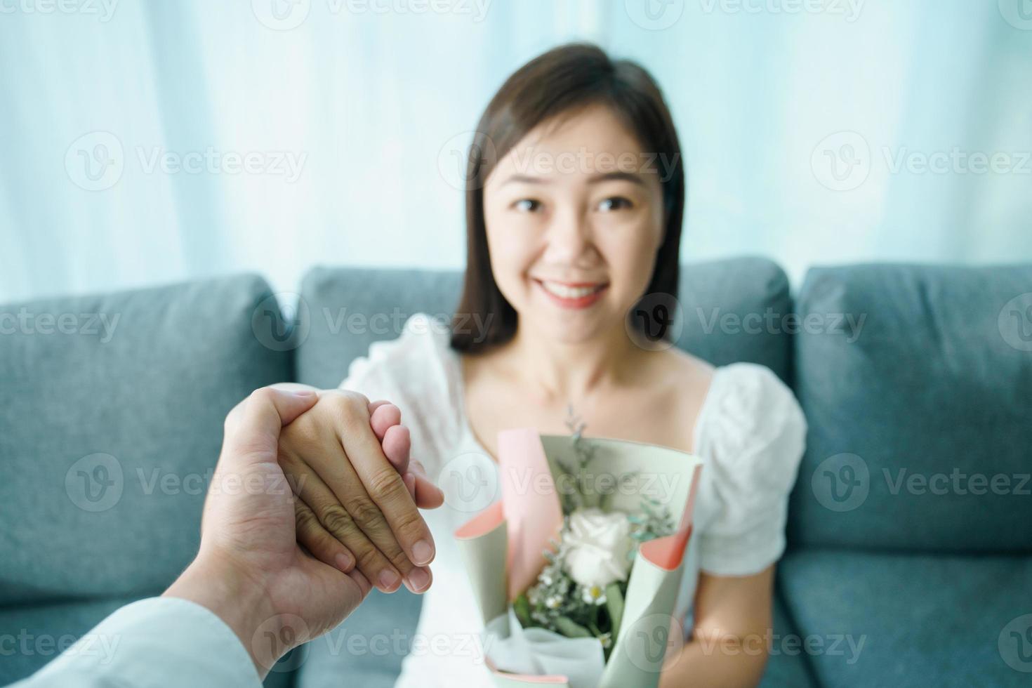 le giovani coppie asiatiche felici in San Valentino o anniversario stanno insieme, l'uomo dà e sorprende sua moglie un bouquet nel loro giorno di San Valentino o anniversario. marito e moglie che festeggiano a san valentino. foto