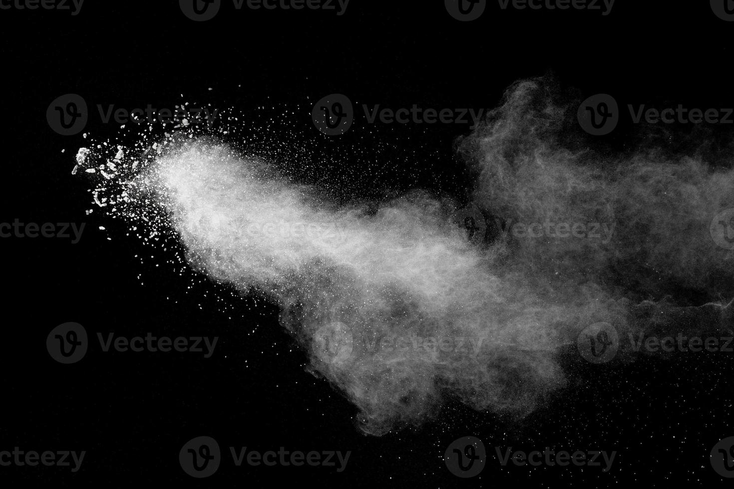 schizzi di polvere bianca. movimento di congelamento del borotalco scoppiato in uno sfondo scuro. foto