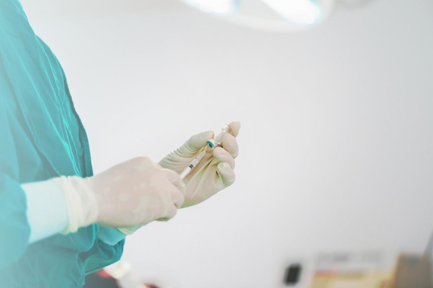 medico che riempie la siringa con il farmaco, la siringa per la tenuta della mano e la fiala del medicinale preparano per l'iniezione in sala operatoria foto