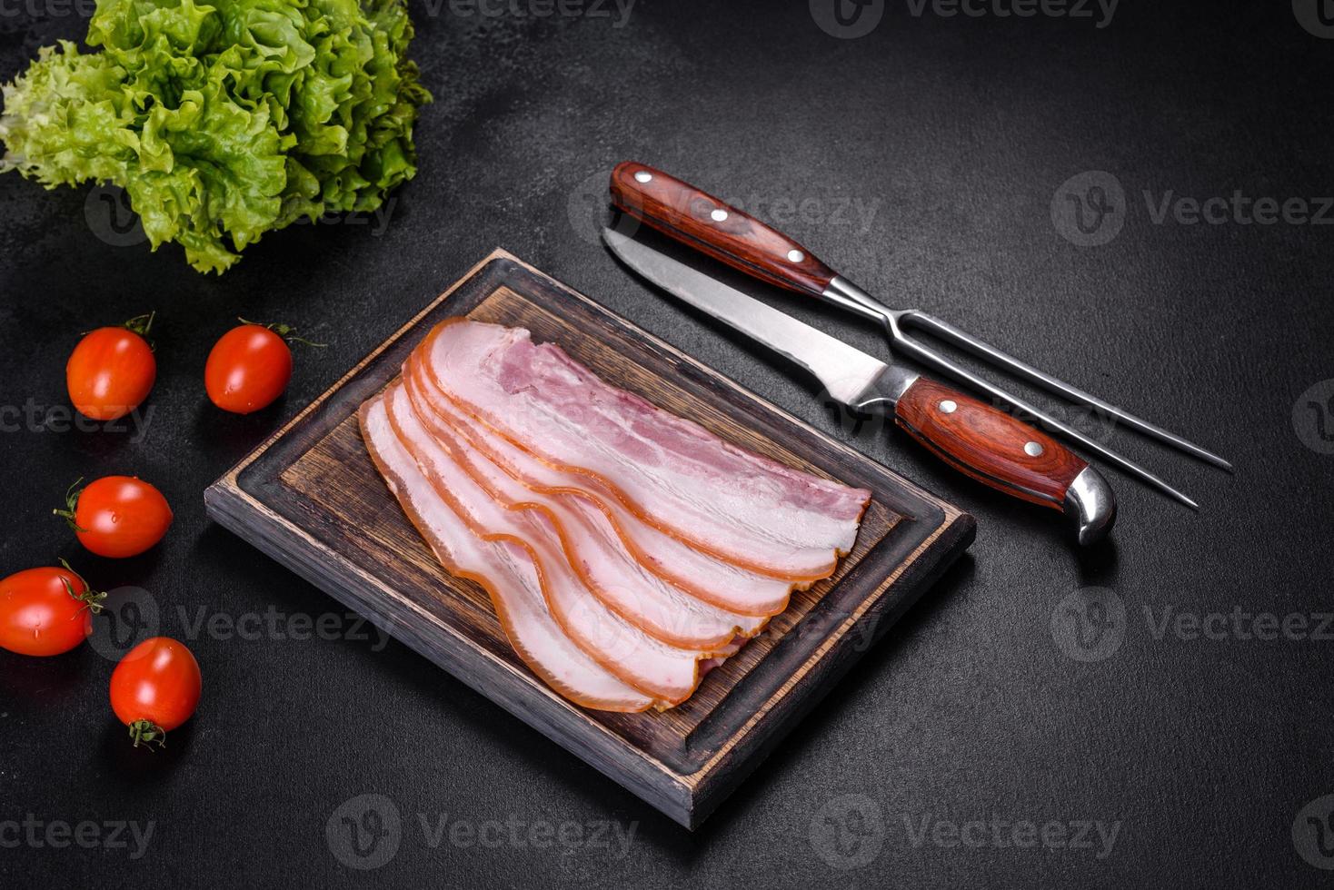 fette di pancetta su un tagliere di legno. carne di maiale foto