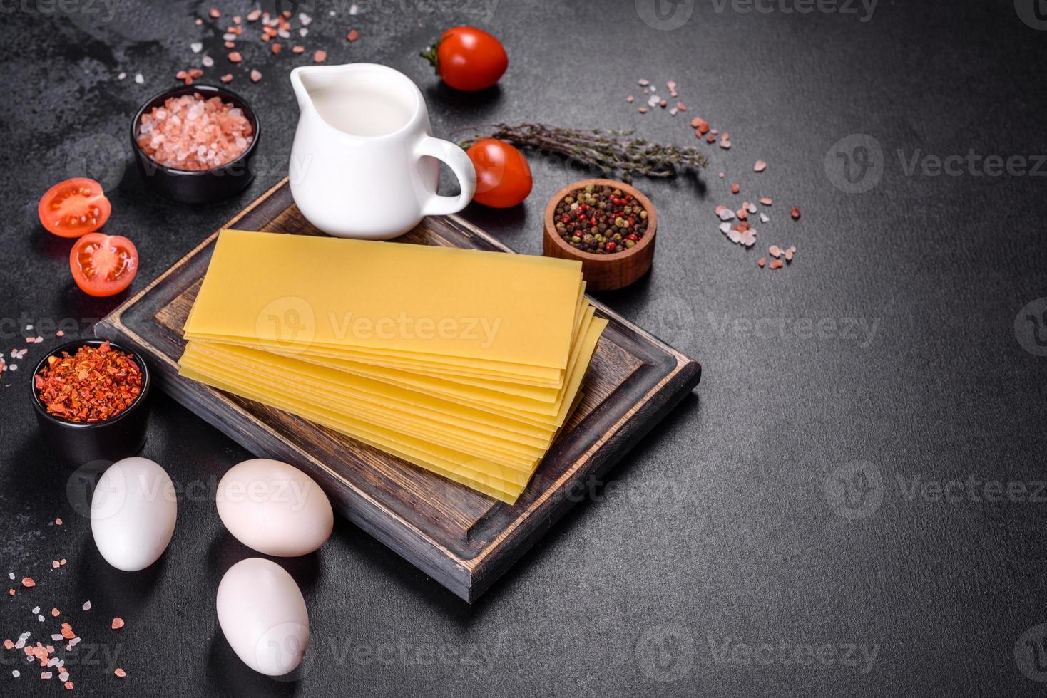 pila di fogli di lasagne su uno sfondo di cemento scuro. ingredienti per lasagne foto