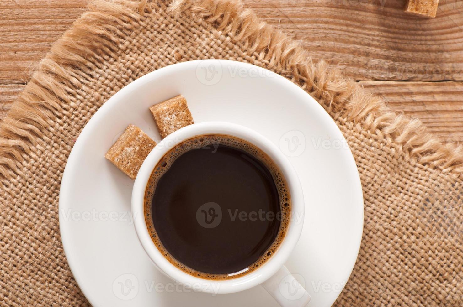 vista del primo piano di una tazza di caffè, zucchero di canna e chicchi di caffè foto