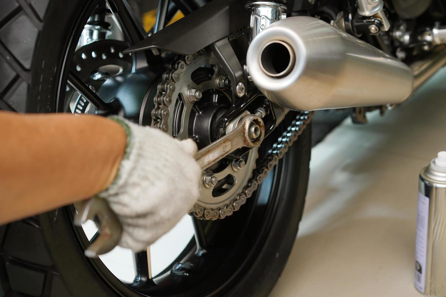 meccanico che utilizza una chiave inglese e una presa sul motore di una motocicletta, manutenzione, riparazione moto concetto in garage .selettivo foto