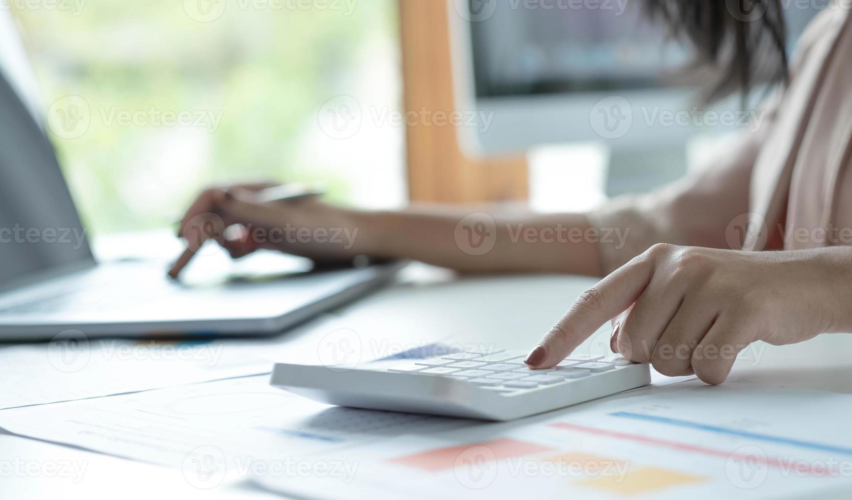 primo piano giovane donna utilizzando calcolatrice e laptop, controllando le bollette domestiche, sedendosi a tavola con documenti finanziari, gestendo il budget di pianificazione, le spese contabili, navigando nel servizio Internet foto