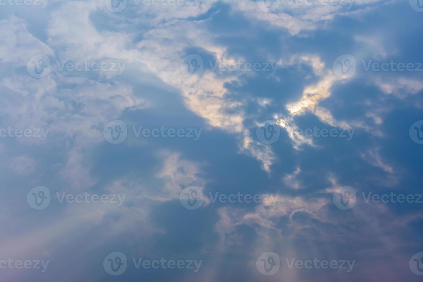 cielo nuvoloso blu a mezzogiorno, con sole coperto dalla nuvola e raggi divini foto